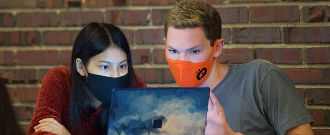Students wearing masks look at laptop